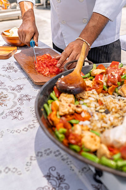 istock Chef slicing tomatoes while preparing delicious paella outdoors 2209462406