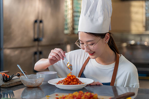 istock Close up of a happy young female chef adding final touch to her dish while working in her kitchen 2209462784