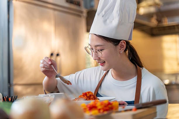 istock Close up of a happy young female chef adding final touch to her dish while working in her kitchen 2209462802