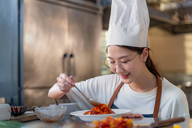 istock Close up of a happy young female chef adding final touch to her dish while working in her kitchen 2209462840