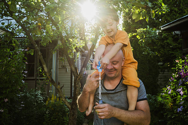 istock Father and son enjoying summer blowing soap bubbles in backyard 2209463573