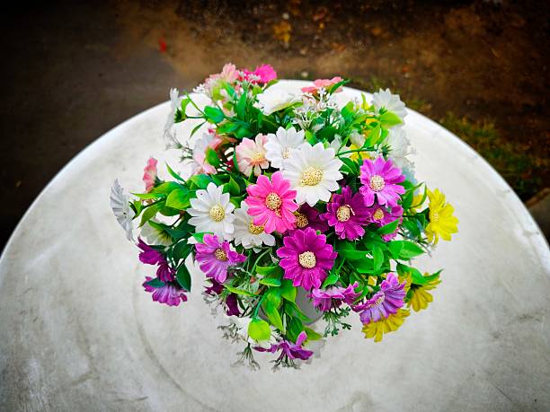 Fake plastic flowersare placed on a white table.