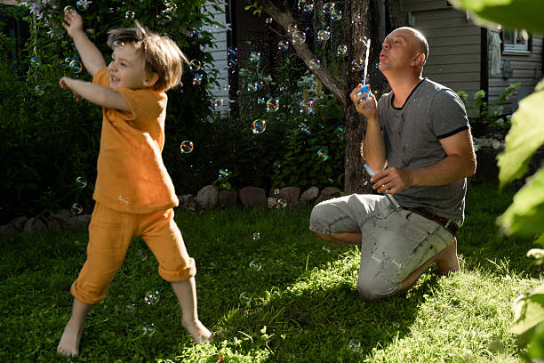istock Father and preschooler having fun blowing bubbles outdoors. 2209464865