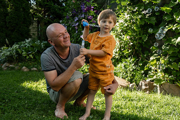 istock Father with son enjoying weekend blowing bubbles outdoors. 2209468354