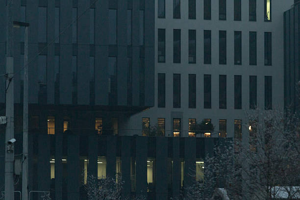 A sleek and modern contemporary building facade featuring illuminated windows against a striking dark exterior.