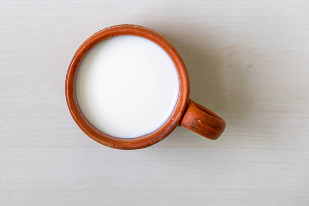 istock A clay cup filled with fresh cow's milk on a light wooden surface. Top view. 2209475730