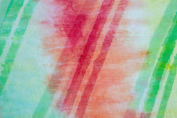 Red, orange, and green tie-dye pattern abstract background. This colorful tie-dye features a line stripe pattern on cotton fabric, creating an abstract texture design.