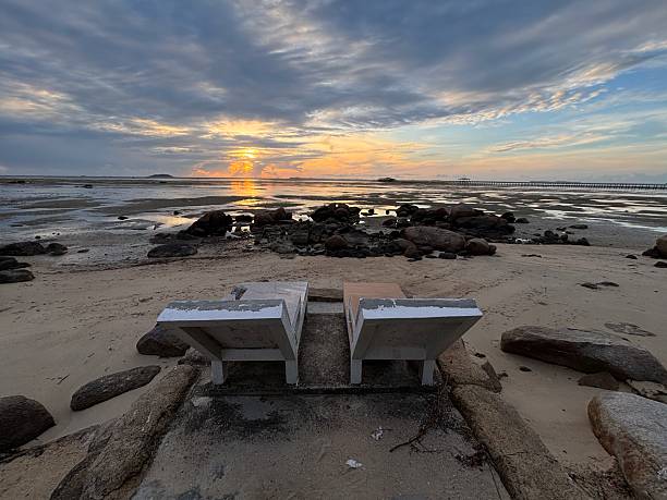 empty lounge chairs on a sandy beach and poolside cabanas gazing over the calm ocean at sunrise
