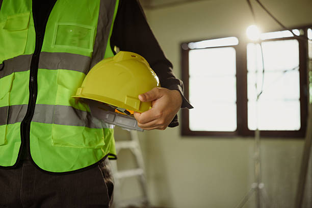istock Engineer in a safety vest holding yellow hard hat at a construction site 2209476521