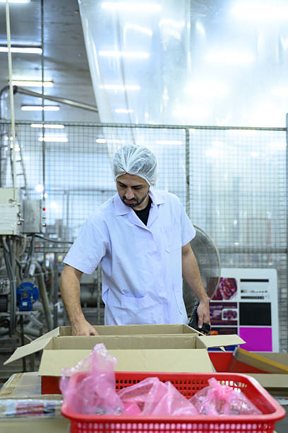 istock Factory worker sorting products in packaging area of a modern food processing plant 2209476620