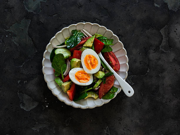 istock Delicious breakfast, snack - boiled egg, fresh vegetable salad on a dark background, top view 2209483159
