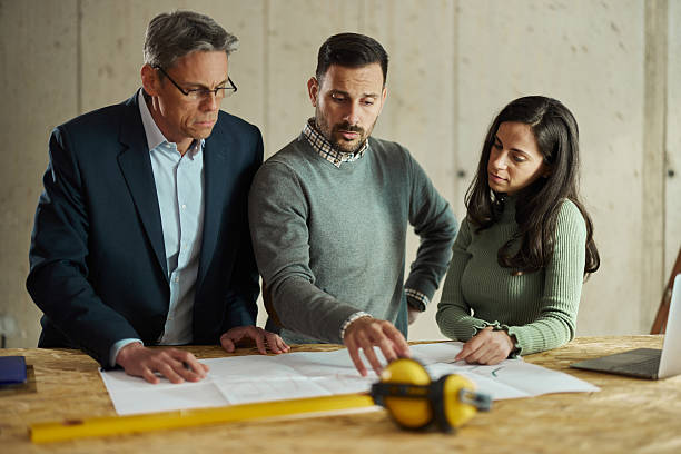 istock Young couple and their agent examining blueprints at construction site. 2209485415