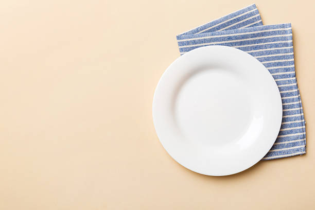 istock Top view on colored background empty round white plate on tablecloth for food. Empty dish on napkin with space for your design 2209485875