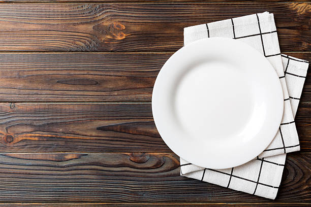 istock Top view on colored background empty round white plate on tablecloth for food. Empty dish on napkin with space for your design 2209485879
