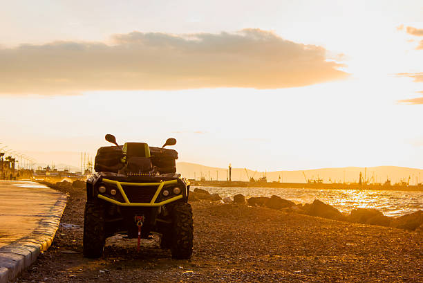 ATV parked by the sea in coastline. Atv vehicle foreground and sunset view at background.