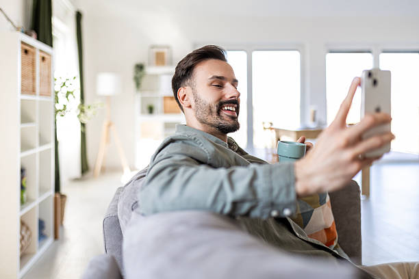 istock Relaxed Guy Browsing Smartphone with Coffee at Home 2209494498