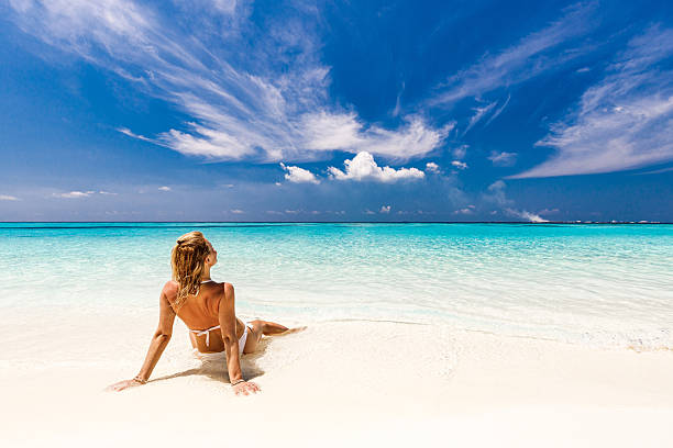 istock Back view of a woman relaxing on the beach. 2209499292