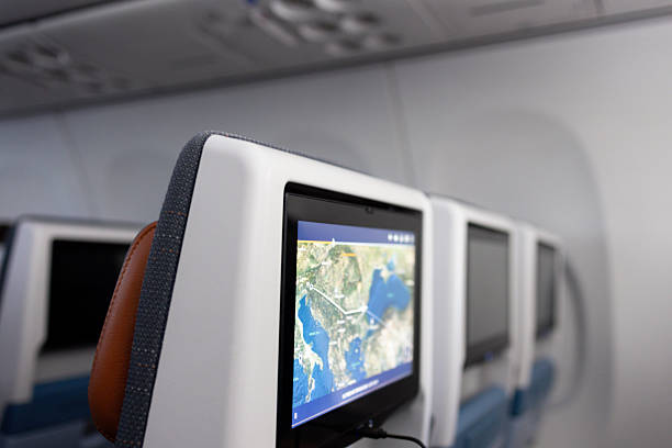 Interior view of a commercial airplane cabin featuring in-flight entertainment screens on the seat backs, one displaying a flight map. The sleek modern seating and soft lighting create a clean and comfortable atmosphere, ideal for topics on air travel, aviation technology, and passenger experience.