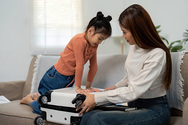 istock Vacation Planning and Family Connect. A child eagerly assists her mother while packing for traveling adventures. 2209500728