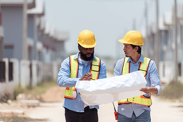 istock Architects and engineers work together to assess the residential home construction site's progress 2209501028
