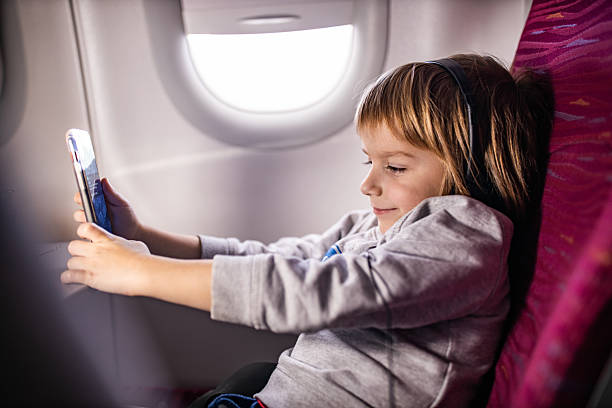 istock Smiling boy watching cartoons on mobile phone in airplane. 2209501419