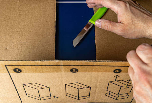 istock Unpacking a large gray cardboard box, knife on a cardboard box, opening a package 2209501755