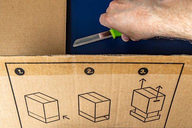 istock Unpacking a large gray cardboard box, knife on a cardboard box, opening a package 2209501923