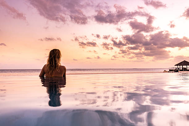 istock Back view of a woman relaxing in infinity pool at sunset. 2209502323