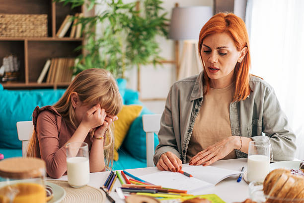 istock Sad elementary school age girl crying while doing homework with her mother 2209506833