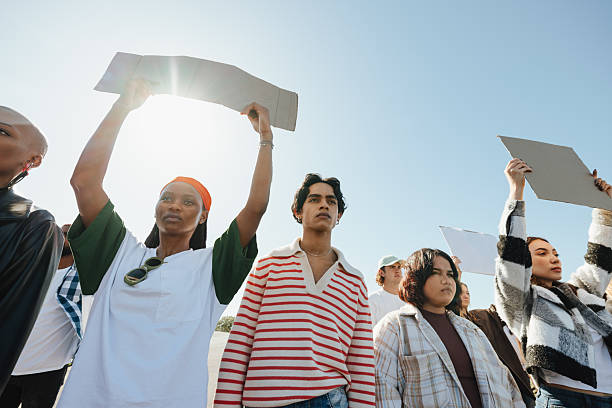 A group of individuals participates in a peaceful demonstration, advocating social justice and equality. They hold signs and show solidarity for the cause while standing under clear skies.