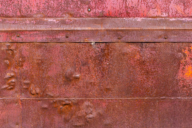 Corroded metal sheets fastened with hex screw heads and welded seams, displaying a range of rust tones - full-frame flat background and texture.