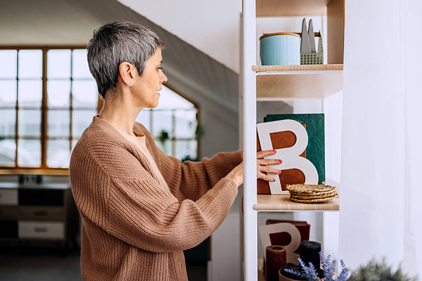 istock Mature woman picking a book from home bookshelf 2209511315