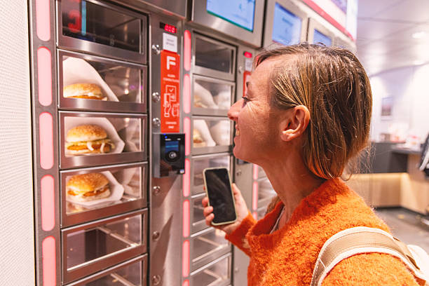 istock Woman using automated food vending machine while smiling 2209513606