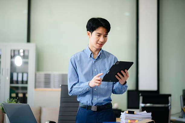 istock Confident  Asian businessman typing laptop computer and digital tablet at office 2209517479