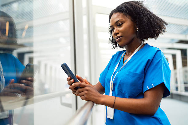 istock Healthcare worker in blue scrubs using mobile phone during break at clinic 2209524156