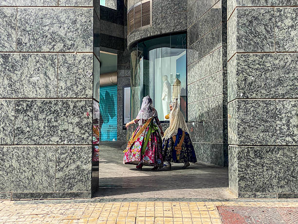 Valencia, Spain - March 19, 2025: Two young girls with traditional 'fallera' dresses walking in the street. Las Fallas is an annual event celebrated in the Valencian Community during the month of March