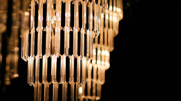 A refined interior scene featuring sparkling crystal chandeliers illuminating a beautifully decorated table. The combination of shimmering lighting and sophisticated decor elements creates a luxurious and inviting ambiance, ideal for weddings, fine dining, or upscale event settings. Perfect for themes related to interior design, elegance, and celebration.