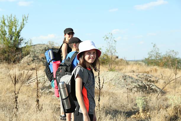 Family with backpacks travelling outdoors on sunny day