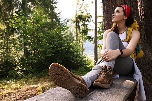 istock Young hiker sitting on wooden bench in forest 2209527832
