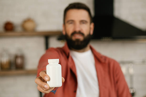 istock Happy young man holding a medicine bottle close up. 2209529125