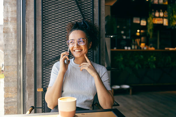 istock Young multicultural woman sitting in coffee shop and having phone conversation. 2209529312