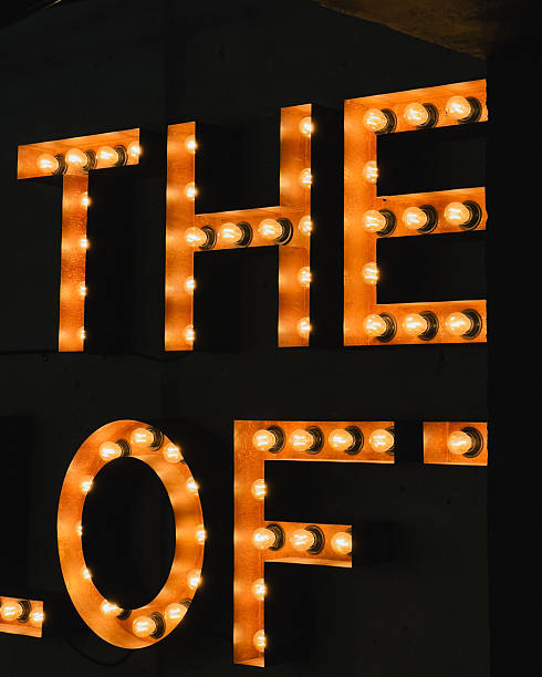 istock Glowing capital letters spelling The Loft emitting warm light, casting soft illumination against shadowy background, creating inviting nighttime signage atmosphere. Large illuminated letters The Loft 2209530023