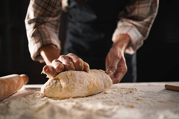 istock Baker kneads dough on floured table, showcasing craftsmanship and passion for breadmaking. entrepreneurship, small business, and artisanal baking 2209530813