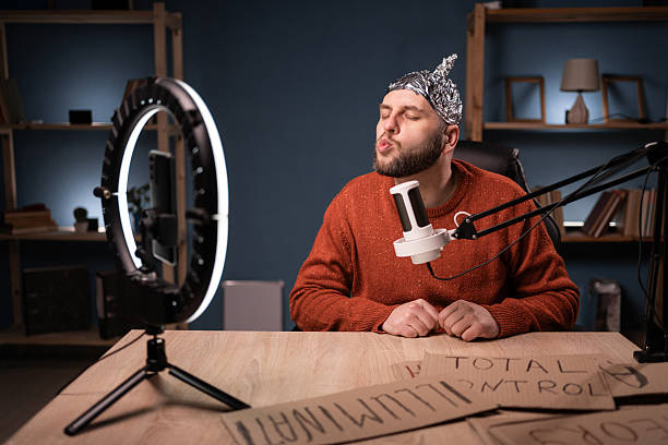istock Crazy conspiracy theorist blogger streaming live at home using smartphone and ring light, showing lips with air kiss on camera 2209530923
