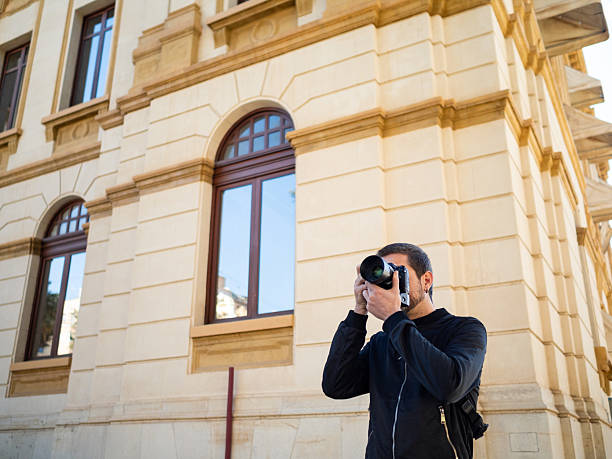 istock Man capturing city architecture with camera on sunny day 2209531902