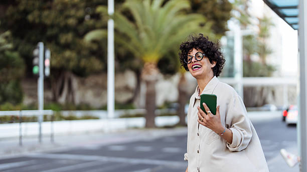 istock Fashionable Woman Smiling Outdoors While Using Smartphone in Urban Environment 2209533397