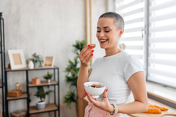 istock Young Woman With A Buzz Cut Eating Cookies While Standing In The Kitchen 2209533682