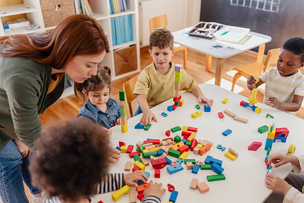 istock Diverse preschool children play with colorful building blocks at a classroom table, guided by a smiling teacher in a creative, inclusive early learning environment. 2209534775