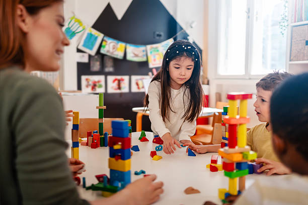 istock Diverse preschool children play with colorful building blocks at a classroom table, guided by a smiling teacher in a creative, inclusive early learning environment. 2209536631