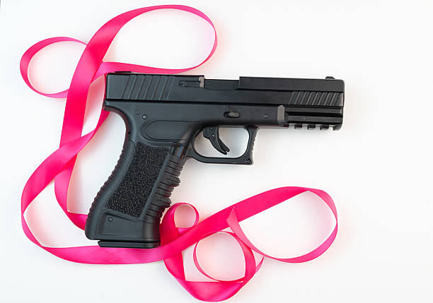Home defense or murderous intent? Young woman points a semiautomatic pistol from the cover of window drapes.
